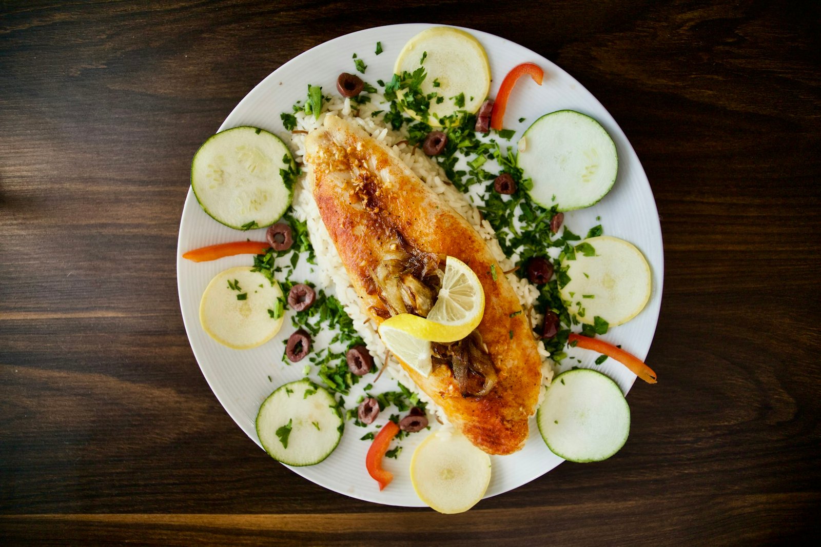 White plate topped with seared fish and vegetables
